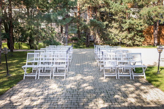 White Wedding Chairs With Bouquets Of Lavender Outdoors. It Is A Lot Of White Stools On A Green Lawn. Wedding Subject. 