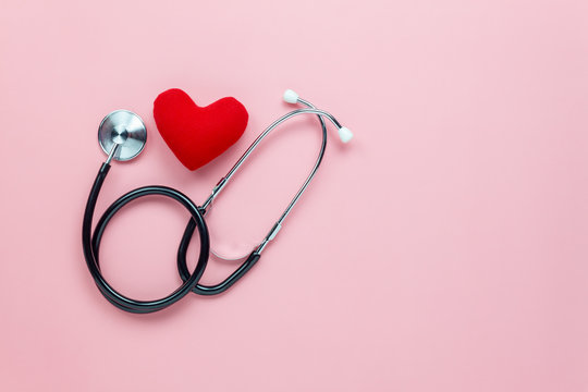 Table top view aerial image of accessories healthcare & medical background concept.Red heart & stethoscope with copyspace on pink paper.Flat lay of idea for doctor treat patient in hospital.