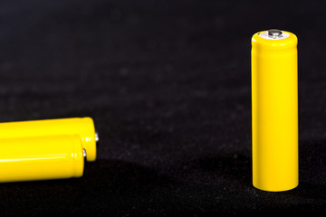 Three yellow batteries close-up on a dark black blurred background. Electrics. Battery power. ...