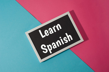 Learn Spanish - text on chalkboard on blue and pink bright background.