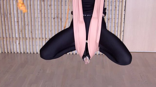 Female legs bent at the knees hang on the canvas during yoga. Above floor hung a woman in a lotus position, which develops flexibility.