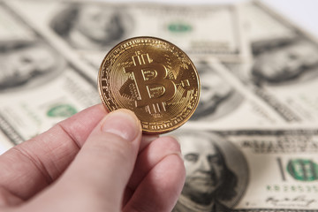 Golden bitcoin coin on us dollars close up.