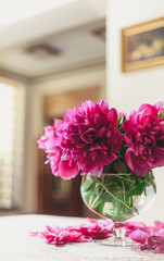 red peonies in glass vase stand on table