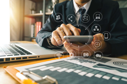 close up of businessman working with smart phone and laptop and digital tablet computer in modern office with virtual icon diagram
