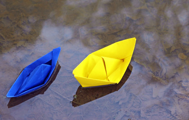 two colorful paper boats in a puddle