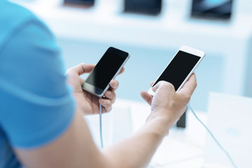 Difficult choice. Professional buyer analyzing two models of smartphone and keeping these in hands while going to choose one