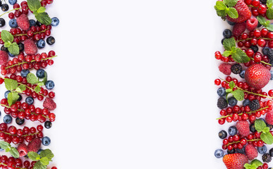 Red and black-blue fruits and berries on a white background. Berries at border of image with copy space for text. Top view. Background berries. Various fresh summer berries.
