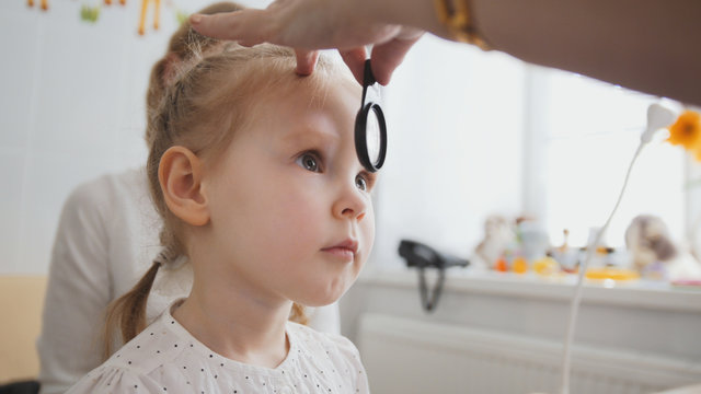 Check up of eyesight in child's ophthalmology - optometrist diagnosis little girl