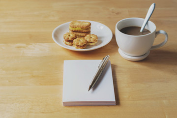 note book with pen and coffee on table