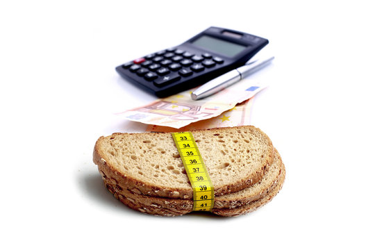 EURO currency with financial calculator and brown slice of breads with measuring tape isolated on white background