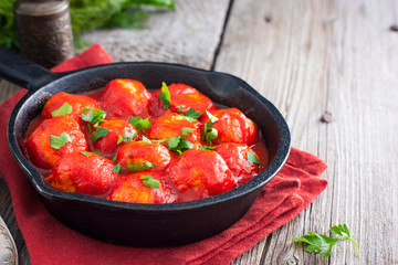 Meatballs in tomato sauce in a cast-iron frying pan on a wooden table, horizontal, copy space