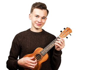 White young guy in sweater play on ukulele in his hands. Isolated on a white background.