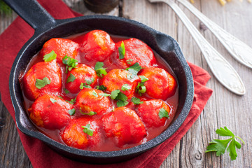 Meatballs in tomato sauce in a cast-iron frying pan on a wooden table, horizontal