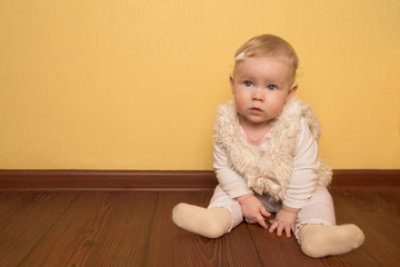 Naklejka premium little girl in beautiful clothes resting sits on a wooden floor in the children's room