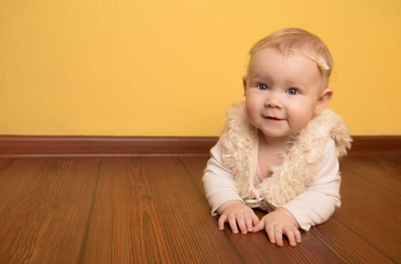  little girl in beautiful clothes resting lies on a wooden floor in the children's room