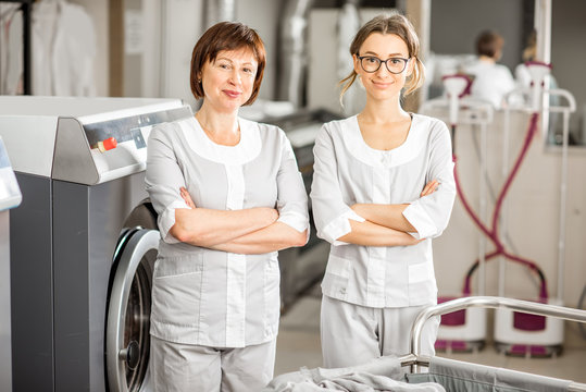 Portrait of a senior washwoman and young assistant standing together in the hotel laundry
