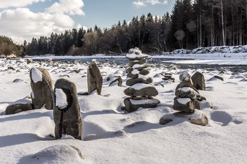 Steinmännchen im tiefen Schnee am Flussufer
