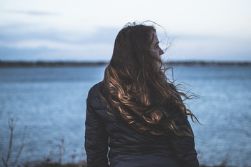 Woman with long brown hair in front of ocean