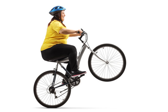 Overweight woman riding a bike and doing a wheelie