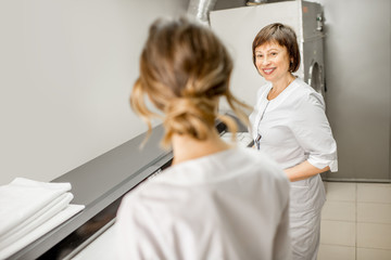 Obraz premium Laundress in unifrom working with professional ironing machine in the laundry