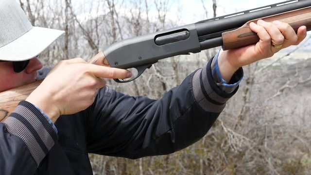 Slow motion of men shooting a clay pigeon with a shotgun
