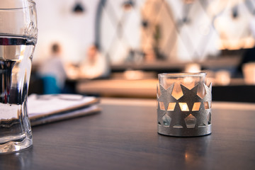 Teelicht mit Sternen in Cafe, Menschen im Hintergrund