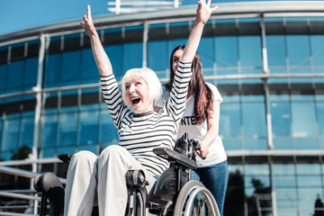 Positive mood. Happy excited cheerful woman holding her arms up and laughing while expressing her...