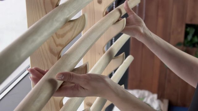 Close up of female hands who is taking wooden katana from stand on the window. Lady is taking the tool to practice her skills in fighting in stylish natural gym. Woman has slim beautiful arms with