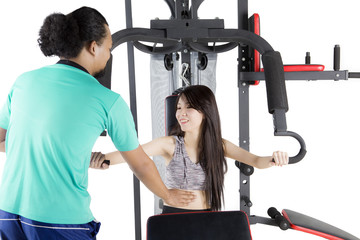 Trainer and girl with weight machine on studio