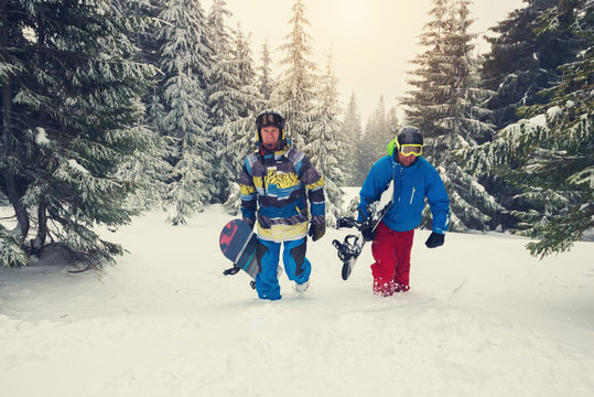 Joyful snowboarders go up the mountain slope