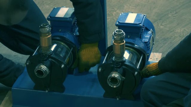 Close-up shot of SKD assembly of water pumps by industrial workers