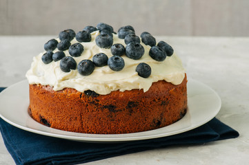 Sour cream blueberry cake served on a plate on a white stone background