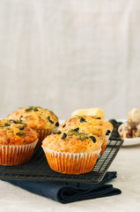 Savory muffins with olives and herbs on a wire rack on a white stone backdrop. Rustic style.