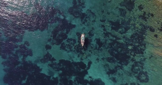 Aerial, a lonely sailing ship in a beautiful bay with crystalline water