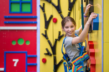 Little girl hanging on holds on climbing wall