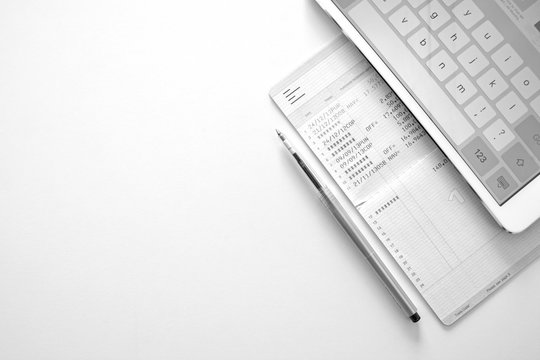 Accountant review number in saving account book bank or statement with data base in computer laptop.