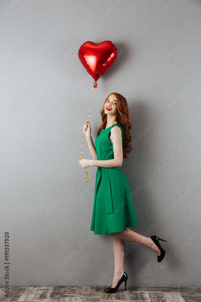 Poster Smiling redhead young holding heart balloon.