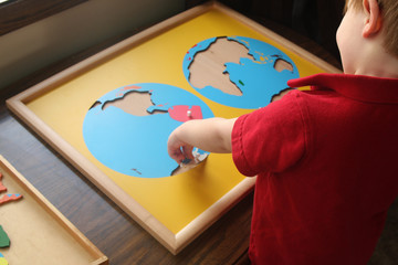 toddler doing montessori continents puzzle © Anna Silverthorn