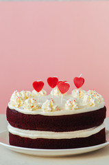 Red velvet cake with cream cheese frosting on a white plate