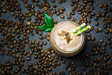 Chocolate mocha breakfast smoothie and coffee beans on dark concrete background. Top view, space for text, close up.