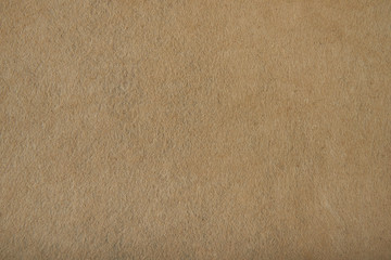 Fragment of the surface of fibrous synthetic non-woven material of light brown color. Background, texture