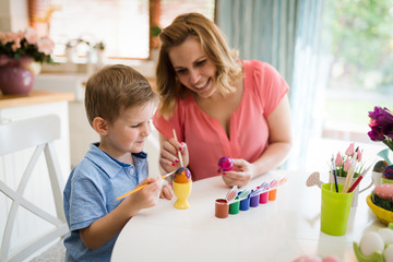 Obraz na płótnie Canvas Mother and her son having fun decorate eggs