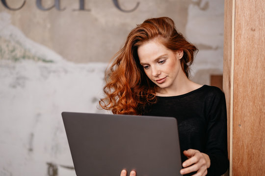 Attractive redhead woman looking at a laptop