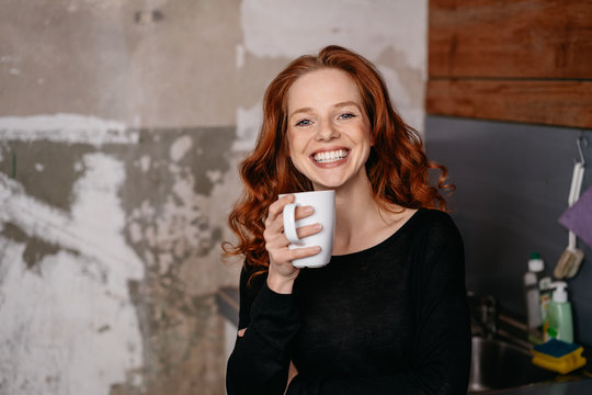 Woman standing in a kitchenette drinking coffee
