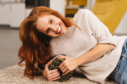 Smiling young woman relaxing on a carpet at home
