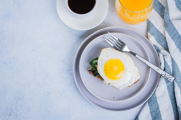 Rye bread toasts with fried spinach and egg with cup of coffee and orange juice on blue table background. Healthy Breakfast Food Concept. Top view with copy space