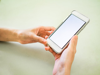 A women is holding mobile phone. Pastel  color background.