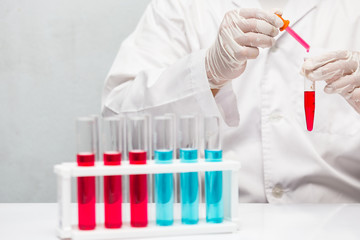 Hand of a chemist  dropping red liquid chemicals in suction to tubes