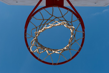 Closeup basketball hoop, basket with white net and blue sky in background