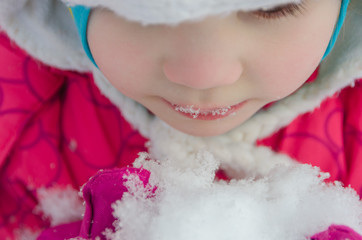  child eats snow in the winter on the street